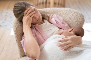 Madre con dolor en el pezón al dar el pecho durante una toma de lactancia
