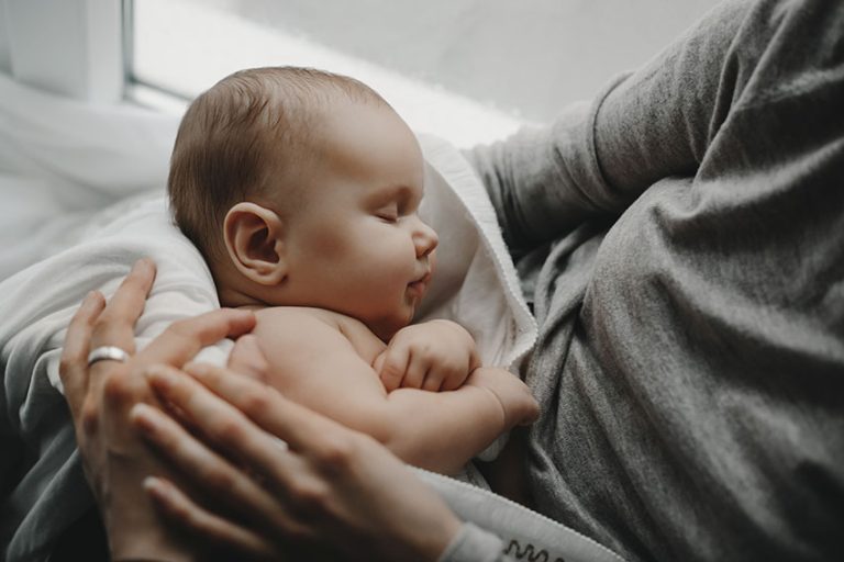 Bebé durmiendo después de una toma nocturna en brazos de su madre